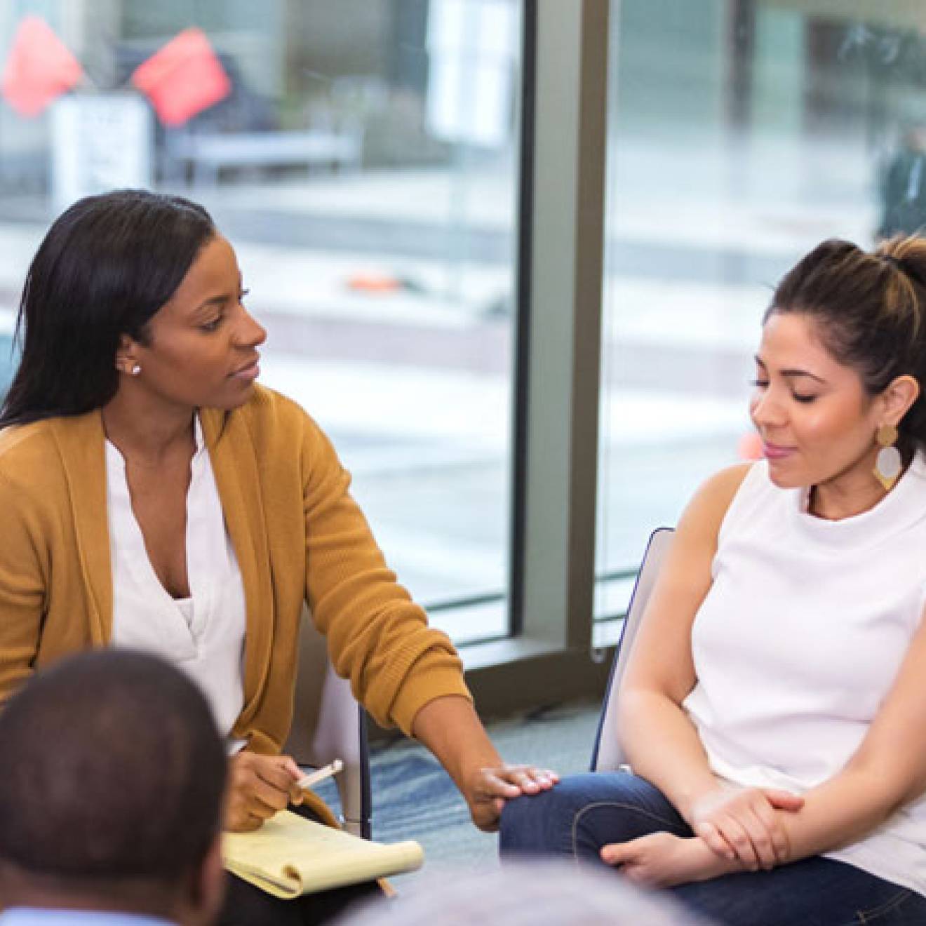 Woman comforts another woman while sitting in a circle