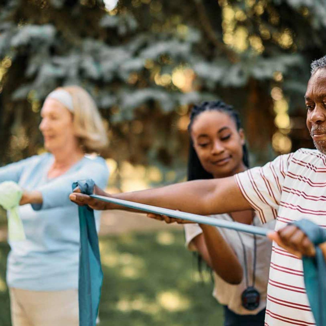 Exercise coach with seniors doing arm exercises with therapy bands