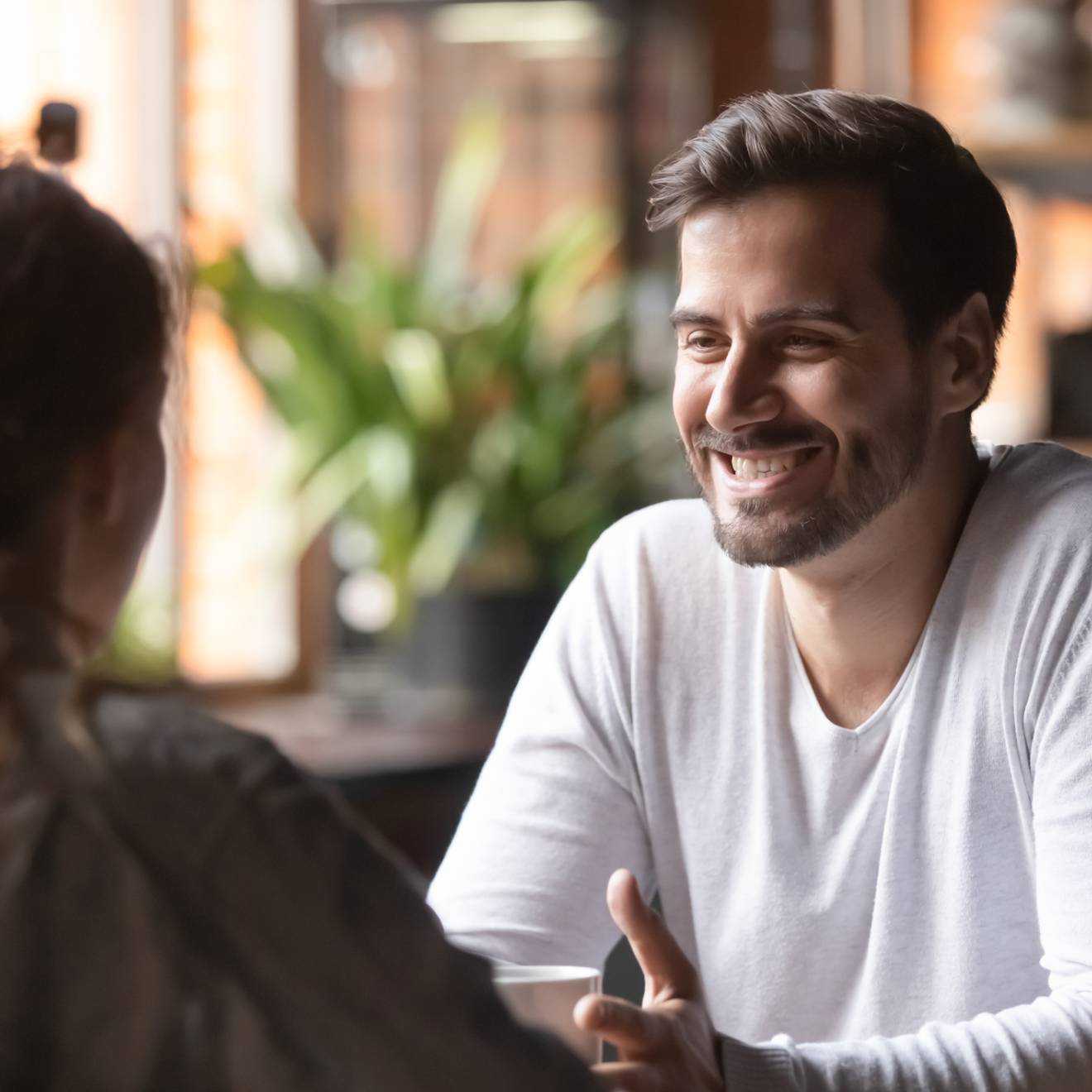 Woman looking at man smiling seated at the same table at a cafe