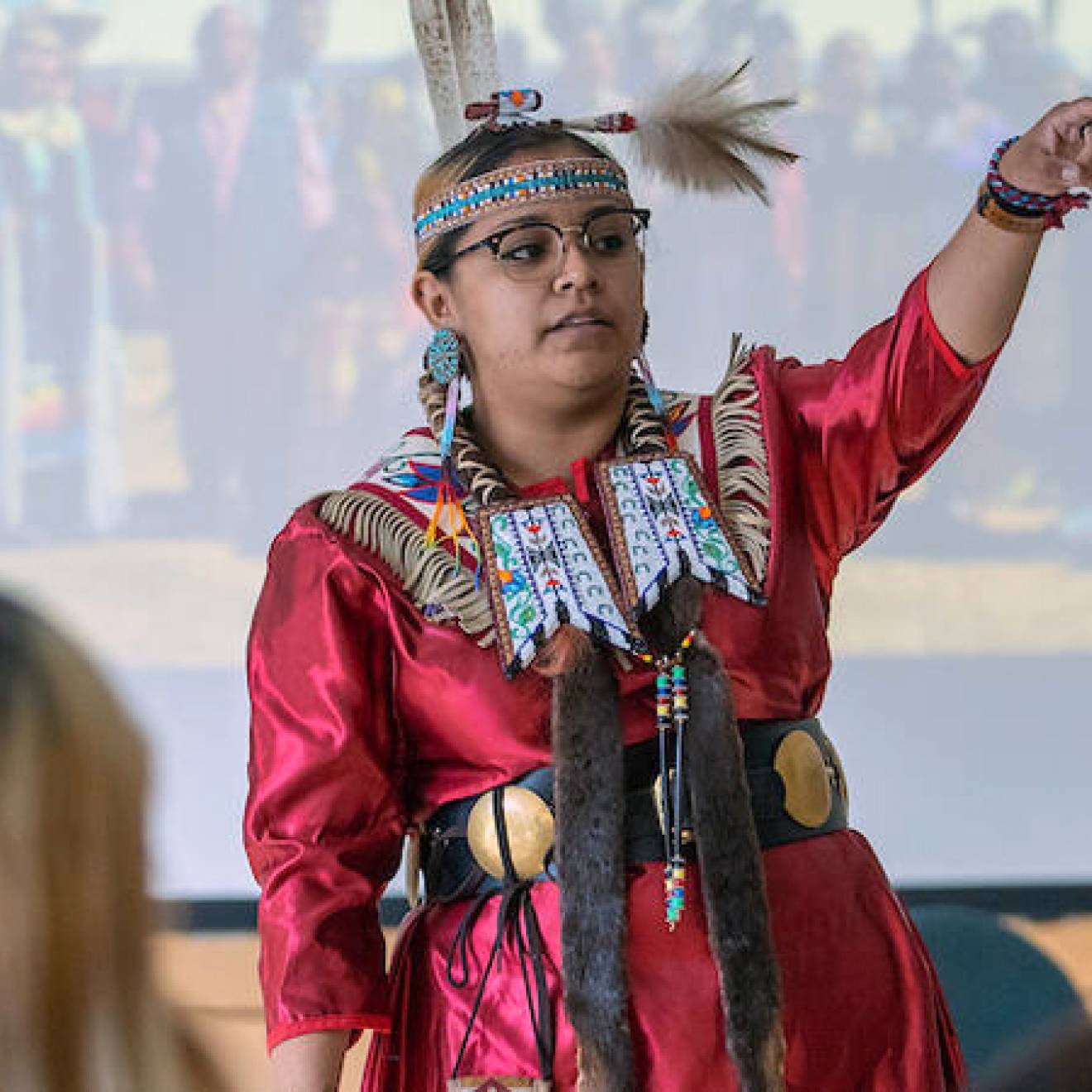 Young woman in tribal dress at the front of a classroom