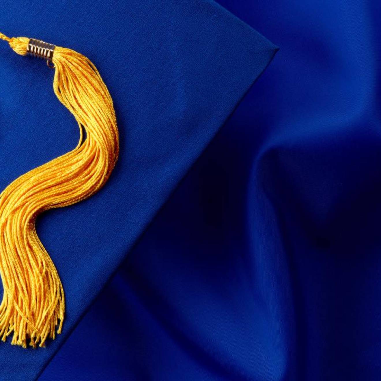 A blue graduation cap with gold tassle