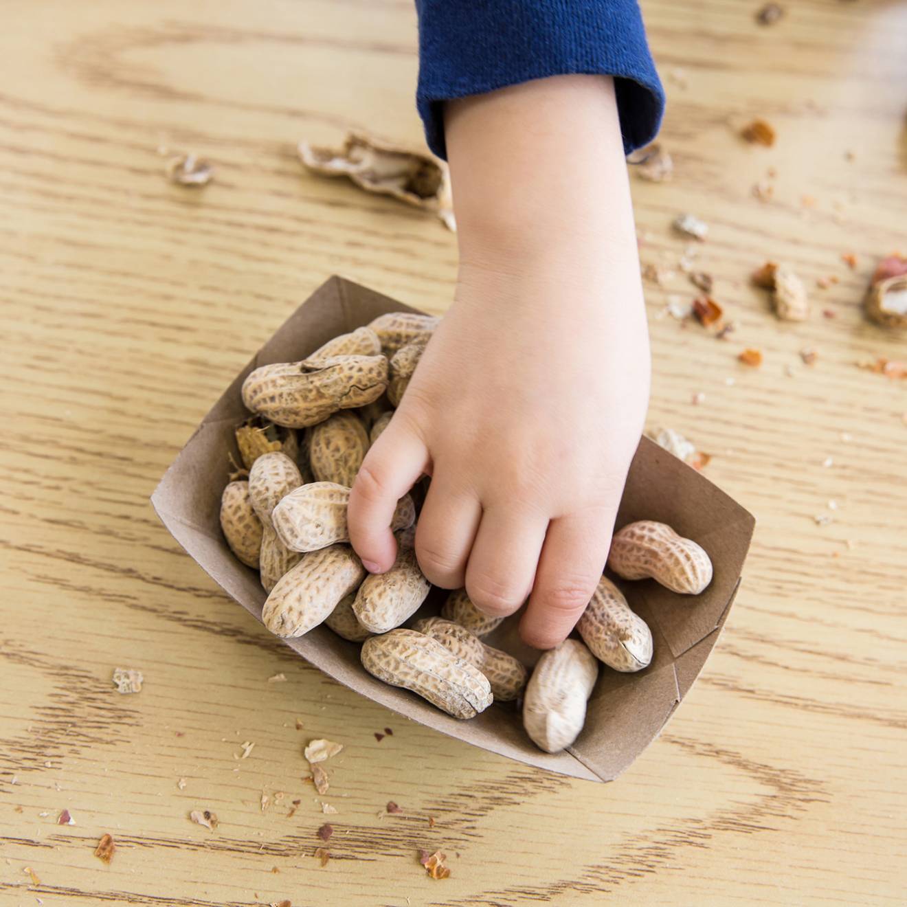 A child's hand reaching for peanuts