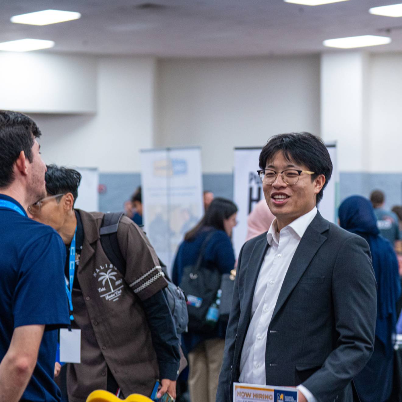A number of people at a career fair with booths indoors