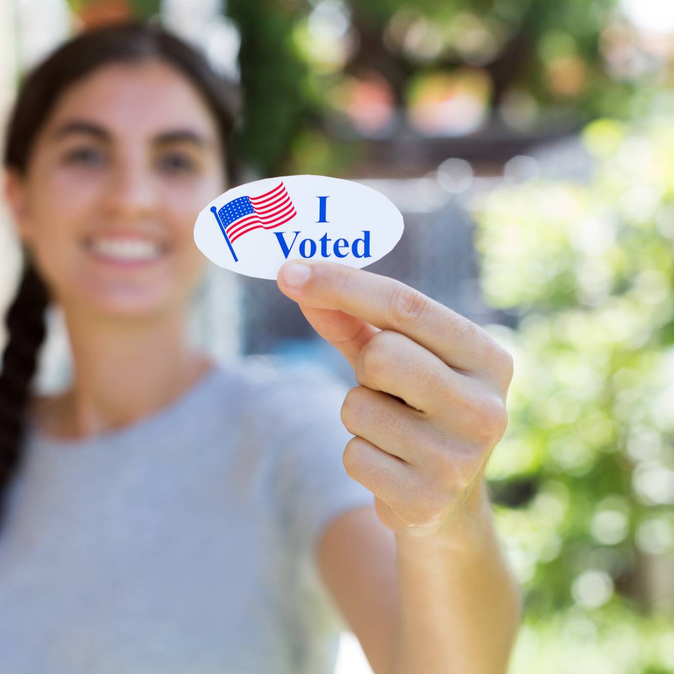 Young woman holding up an I Voted sticker