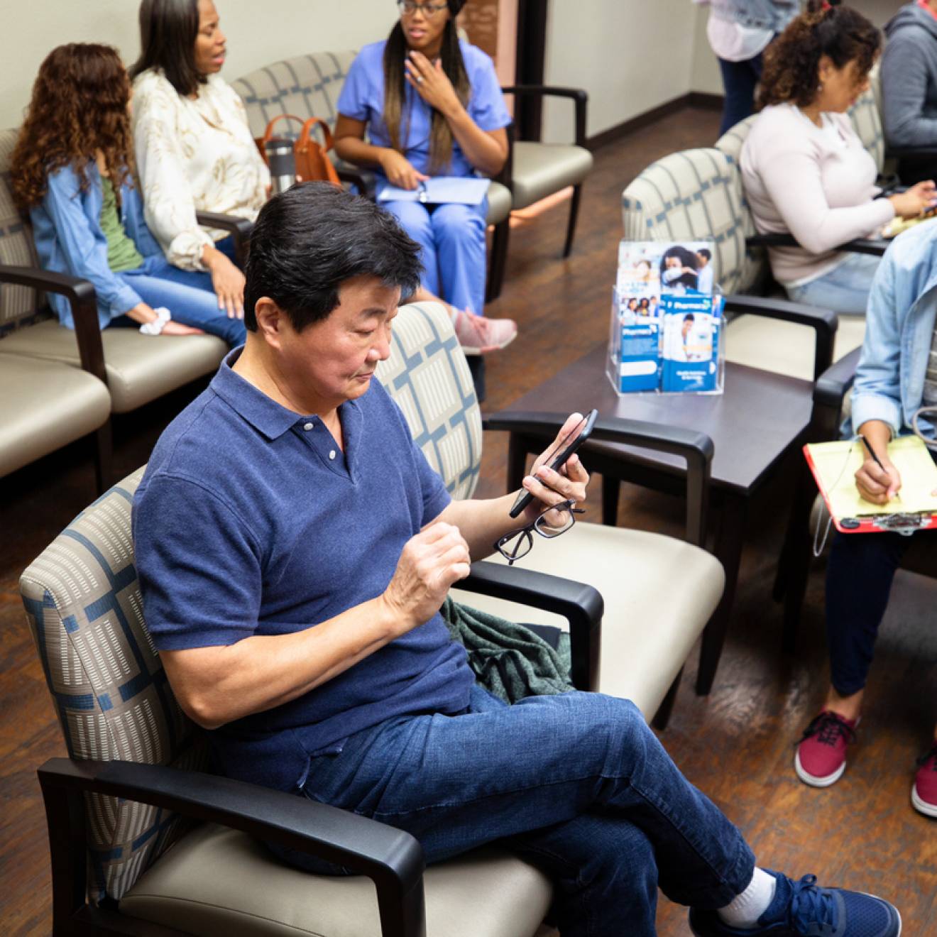 Man looks at his cell phone while waiting at a medical clinic