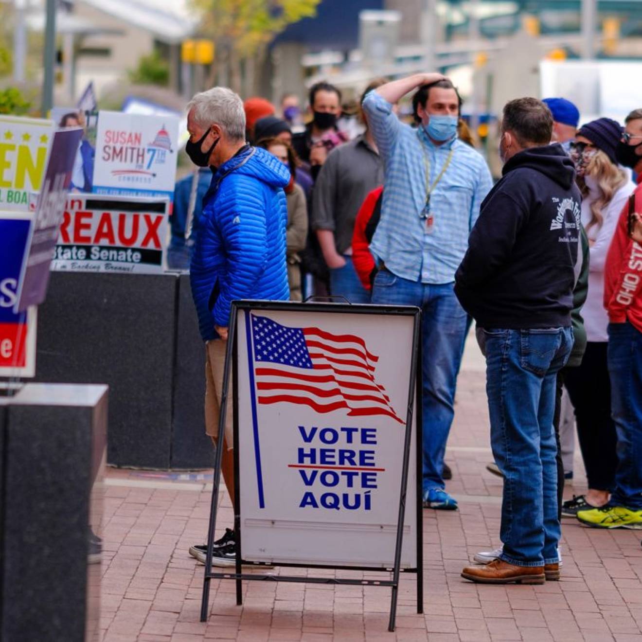 Voters in masks outside a voting station, in masks, looking a little confused