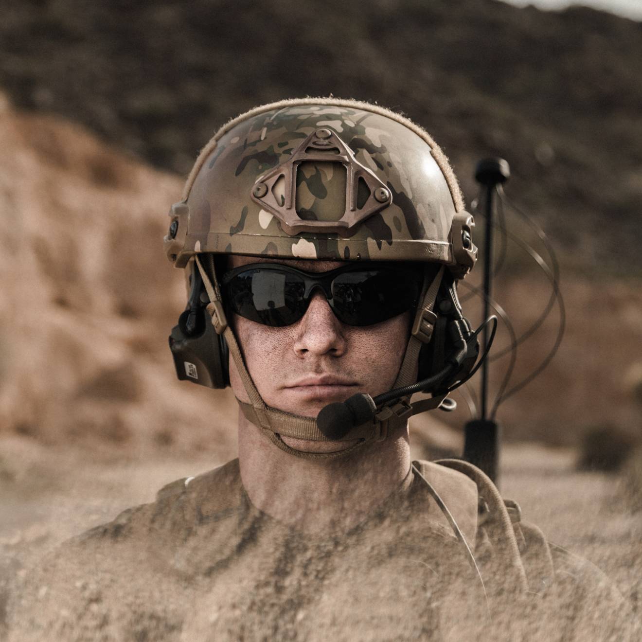 A man with sunglasses in military gear, in a desert