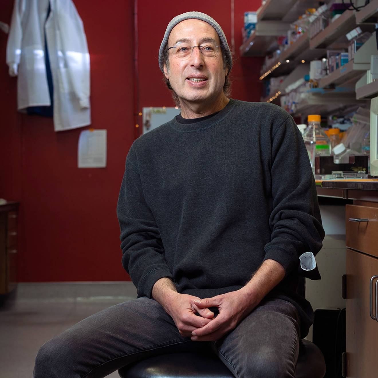 Kenneth S. Kosik seated in the lab, smiling in casual dress