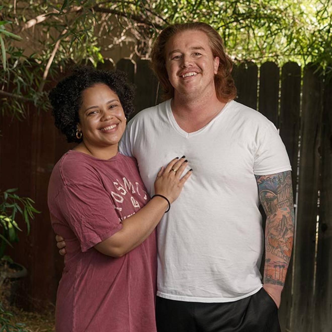 A woman with her hand on the chest of her male partner, who has long red hair