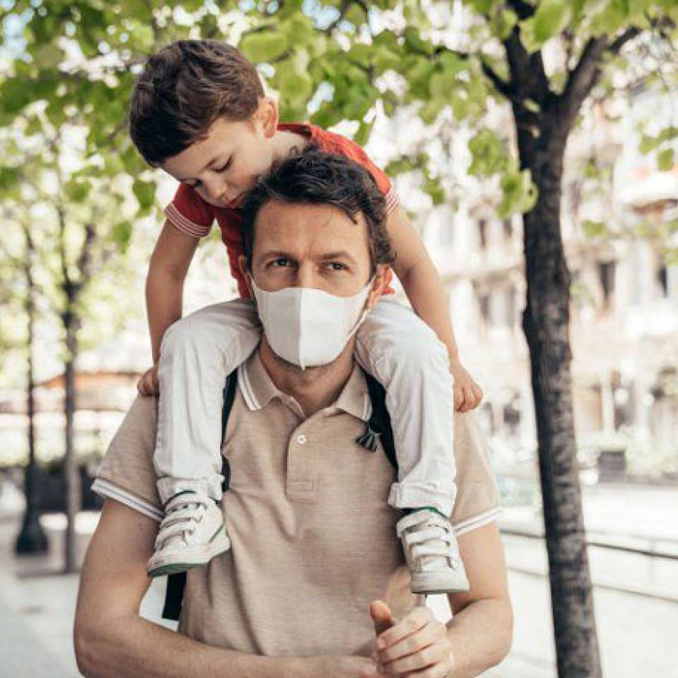 Father wearing a mask carrying a child