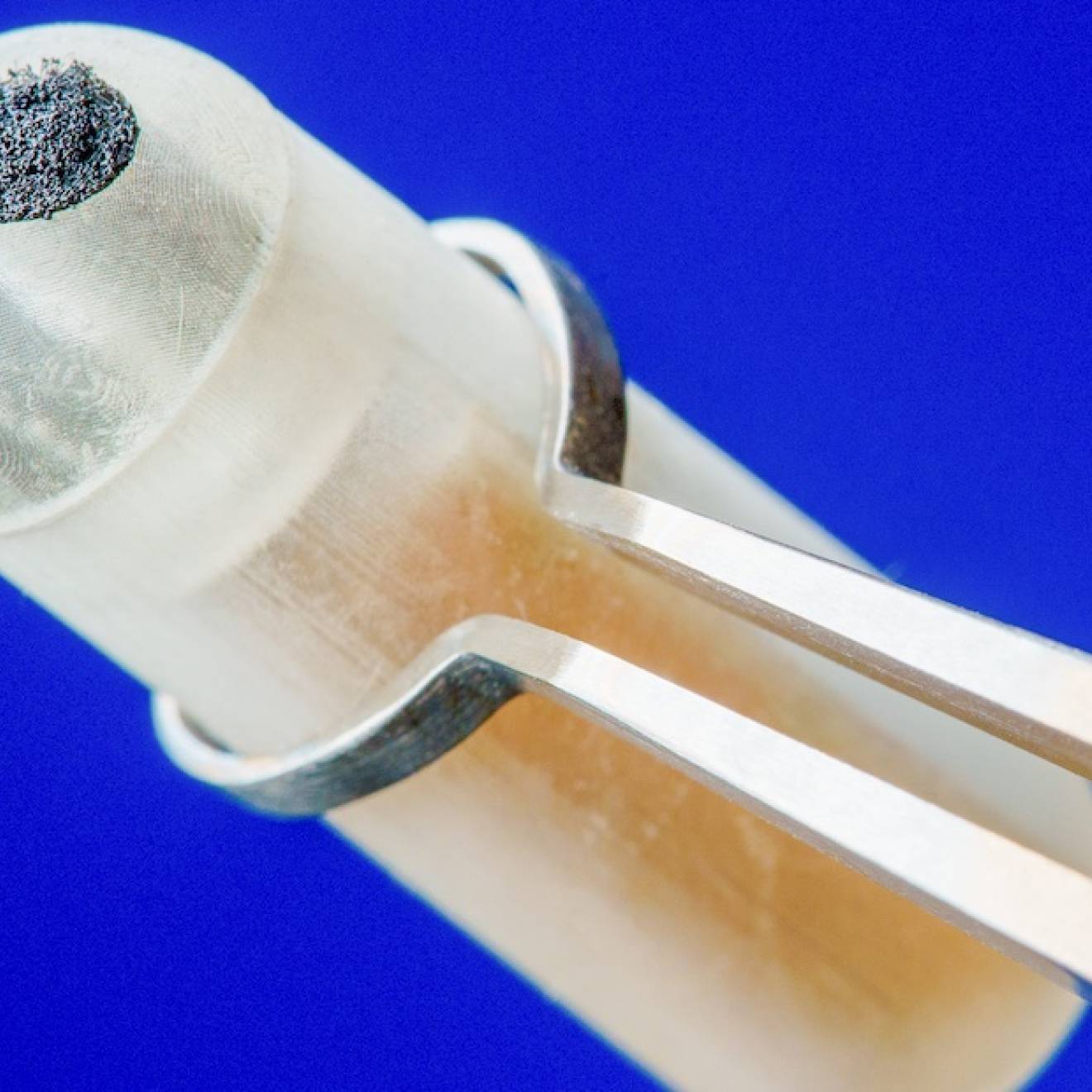 Ingestible sensor held by tweezers, close up