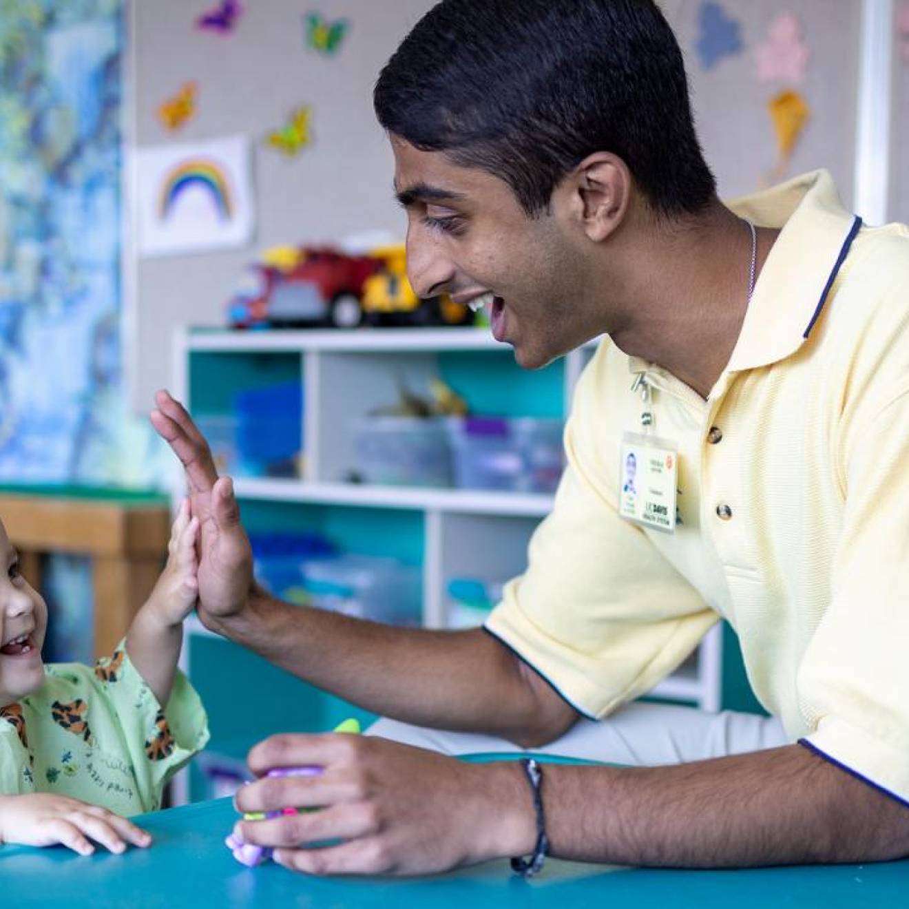 Neeraj Senthil high-fives a laughing baby at the children's hospital
