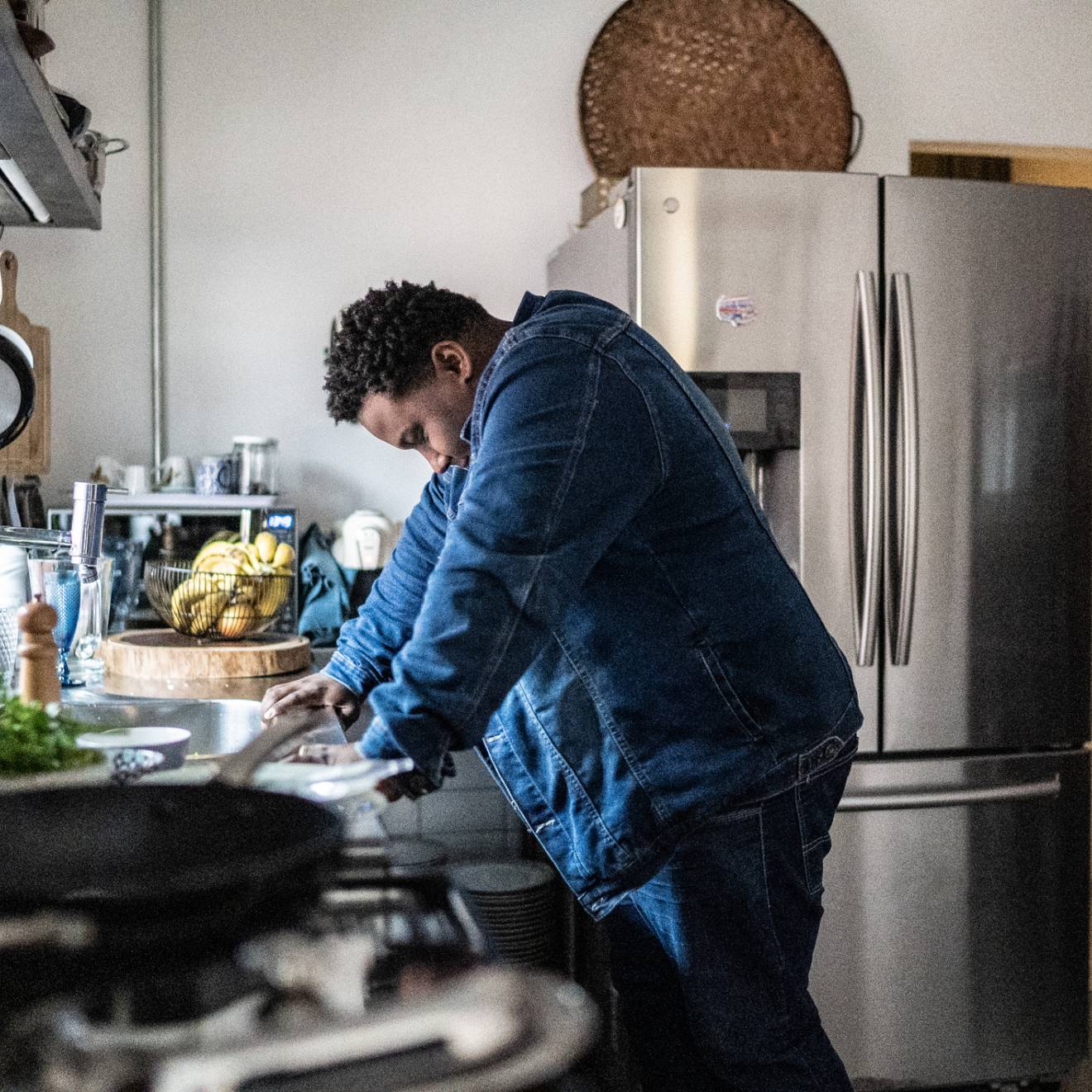 Man leans against counter in a kitchen, looking overwhelmed