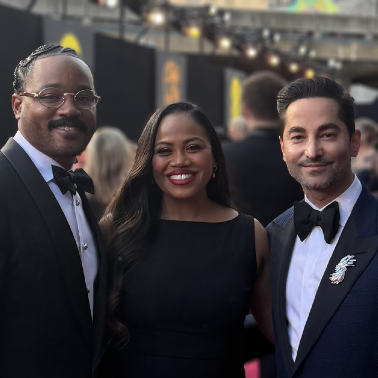 3 people in formal wear on the red carpet