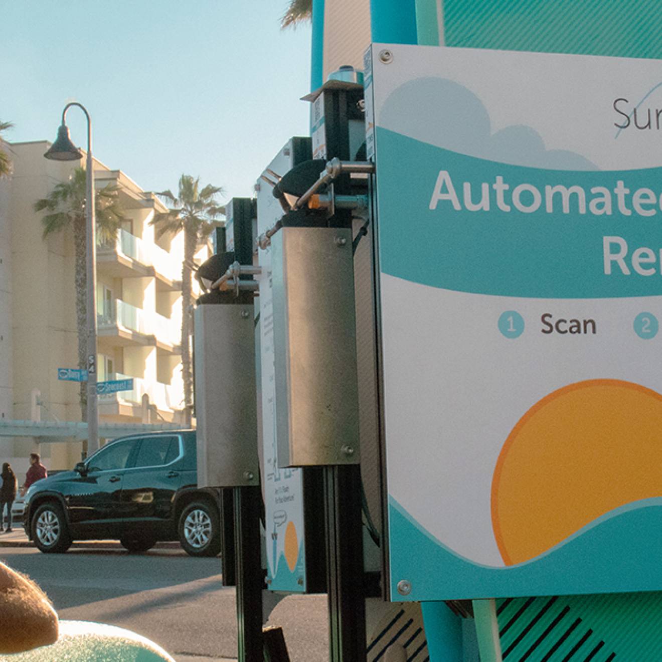 On a sunny day SurfUp co-founder Chris Hissom stands next to one of the four SurfUp surfboard racks currently available outdoors in San Diego