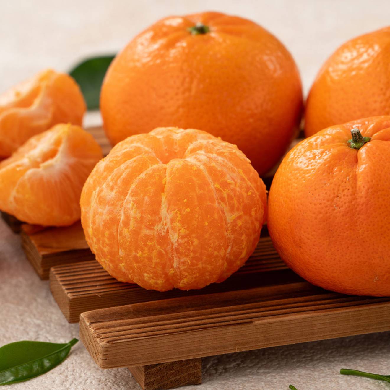 Five mandarin oranges on a cutting board with leaves arranged in a still-life imagte