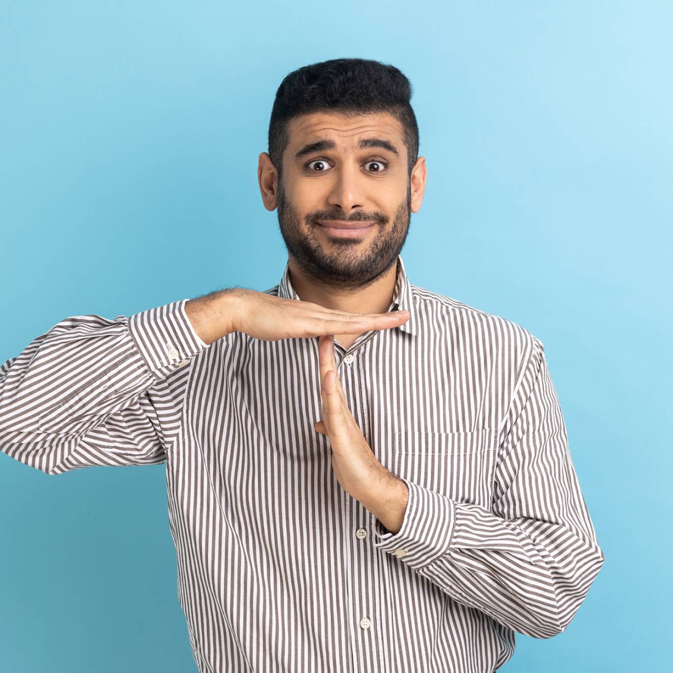 A bearded South Asian man making the timeout gesture