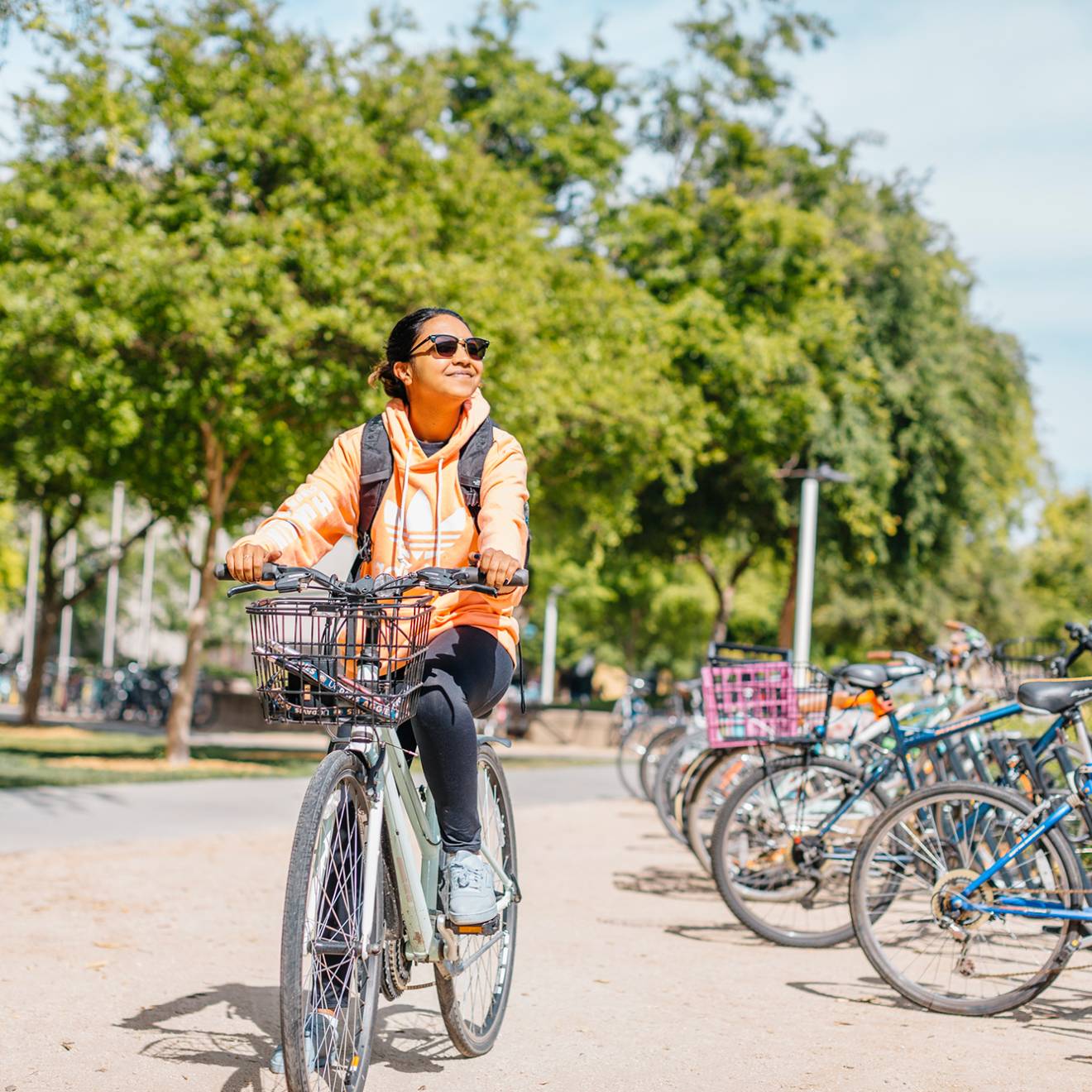 A student smiling in sunglasses riding a bike