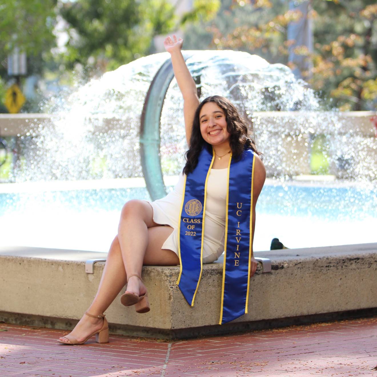 Lili Castillo in her UC Irvine graduation stole in front of a fountain