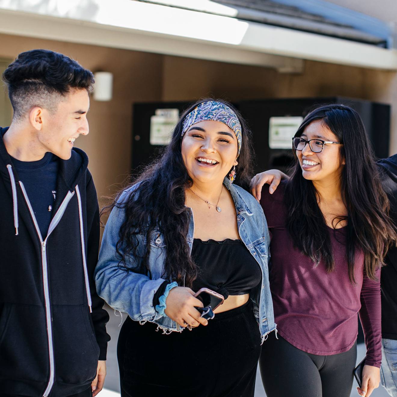 Three students of color smiling and chatting together at UC Merced