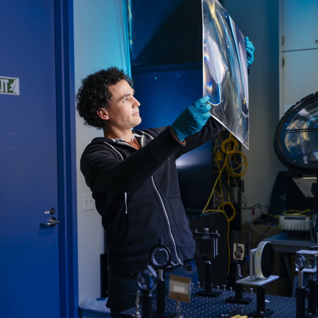 An engineer in a lab holds up a large square of a material to the light