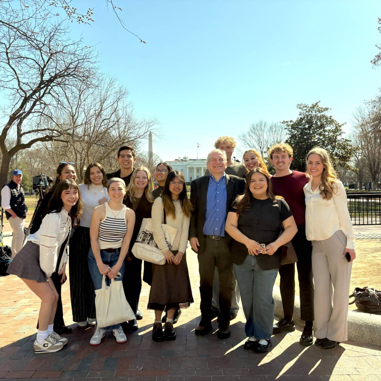 A group photo of people outside, Washington Monument and the White House behind