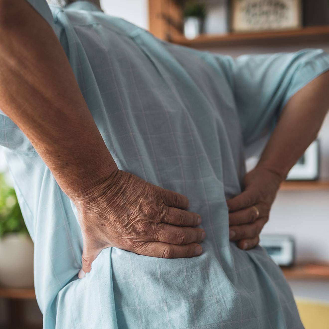 A person holds lower back as if to massage stiffness