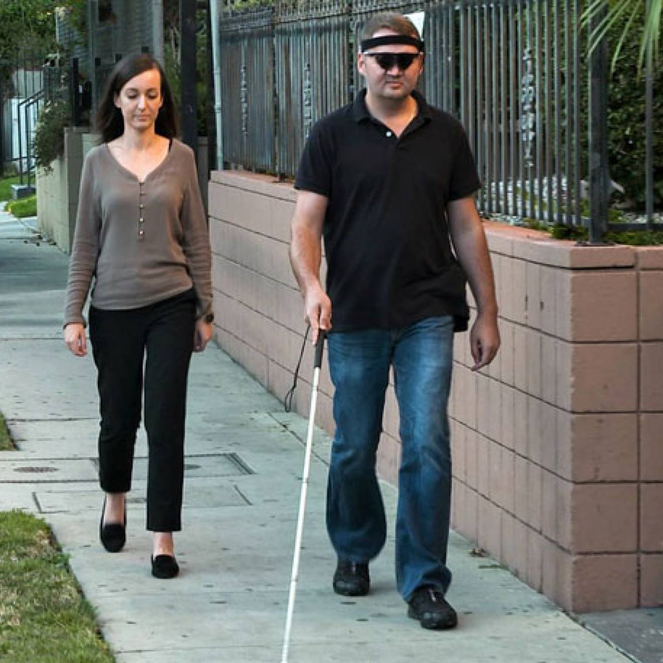 A man with a cane walking with a woman just behind him