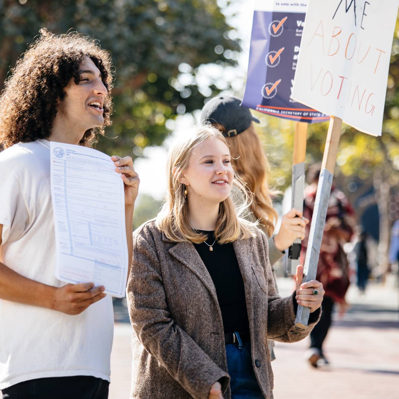 Alex Edgar and Skylar Betts hold up signs to encourage students to register to vote on the UC Berkeley campus