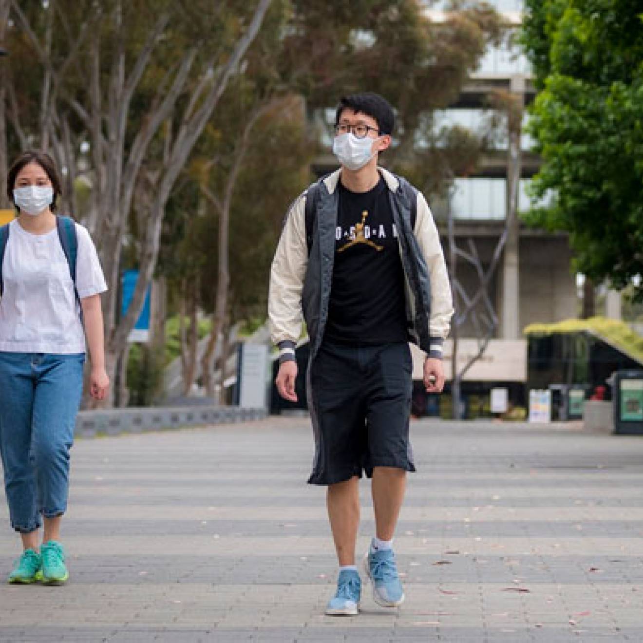 Two students walk with facemasks on