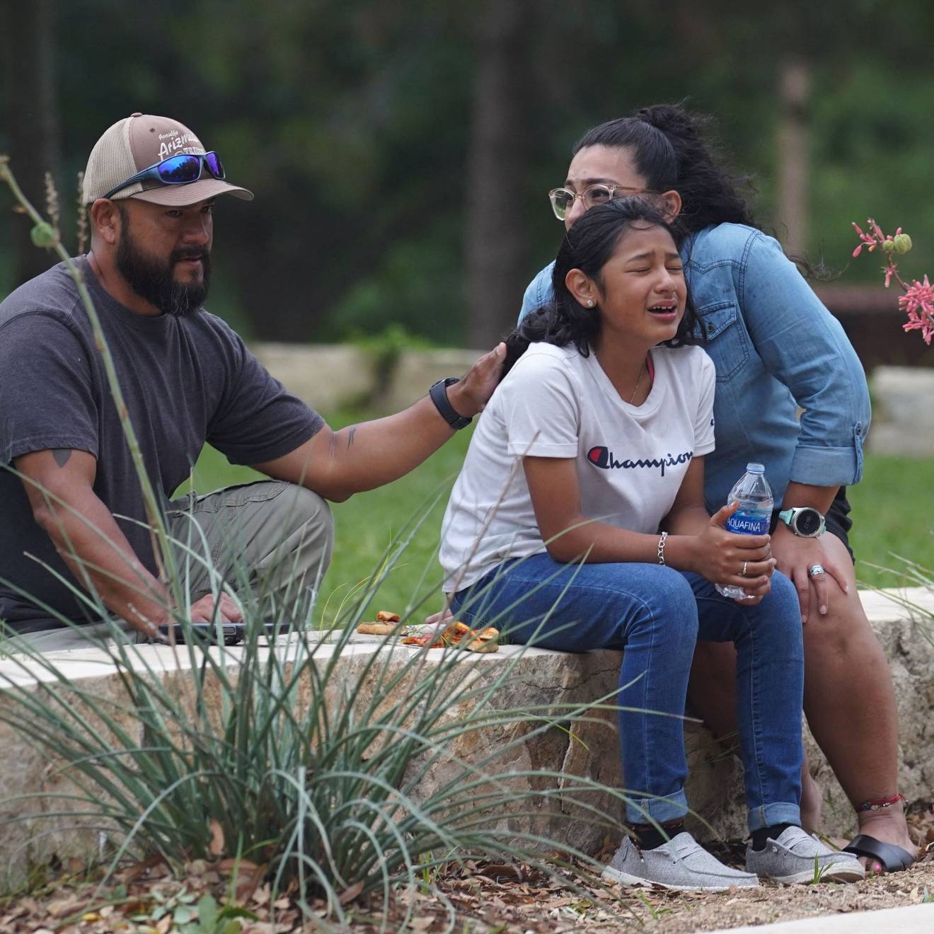 A girl cries outside the Willie de Leon Civic Center in Uvalde, Texas, on May 24, 2022, surrounded by two adults