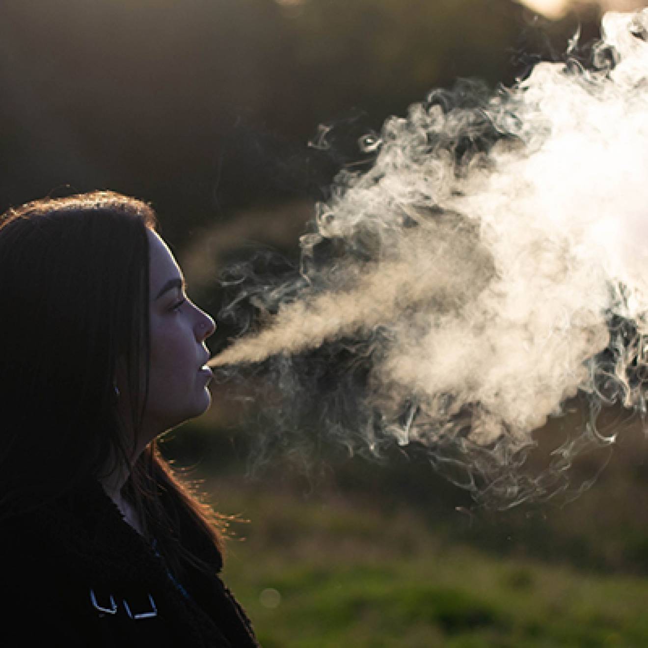 Young woman vaping big cloud of smoke
