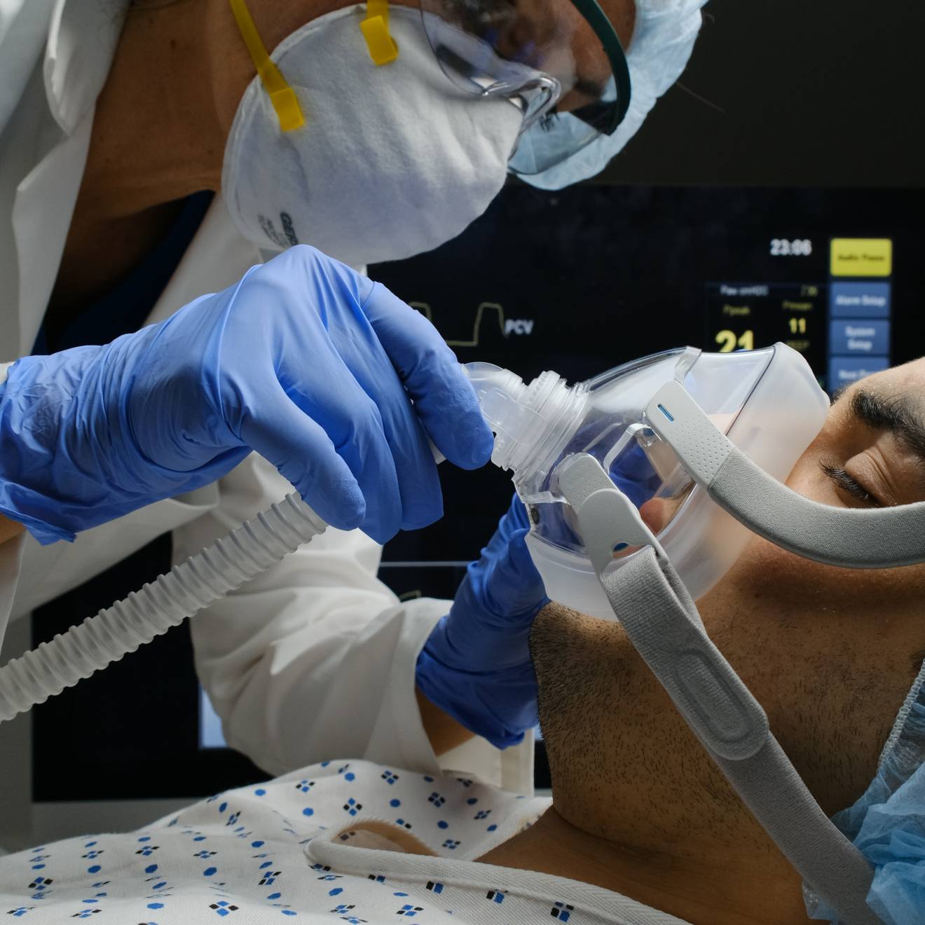A COVID-19 patient on a ventilator being checked by a doctor
