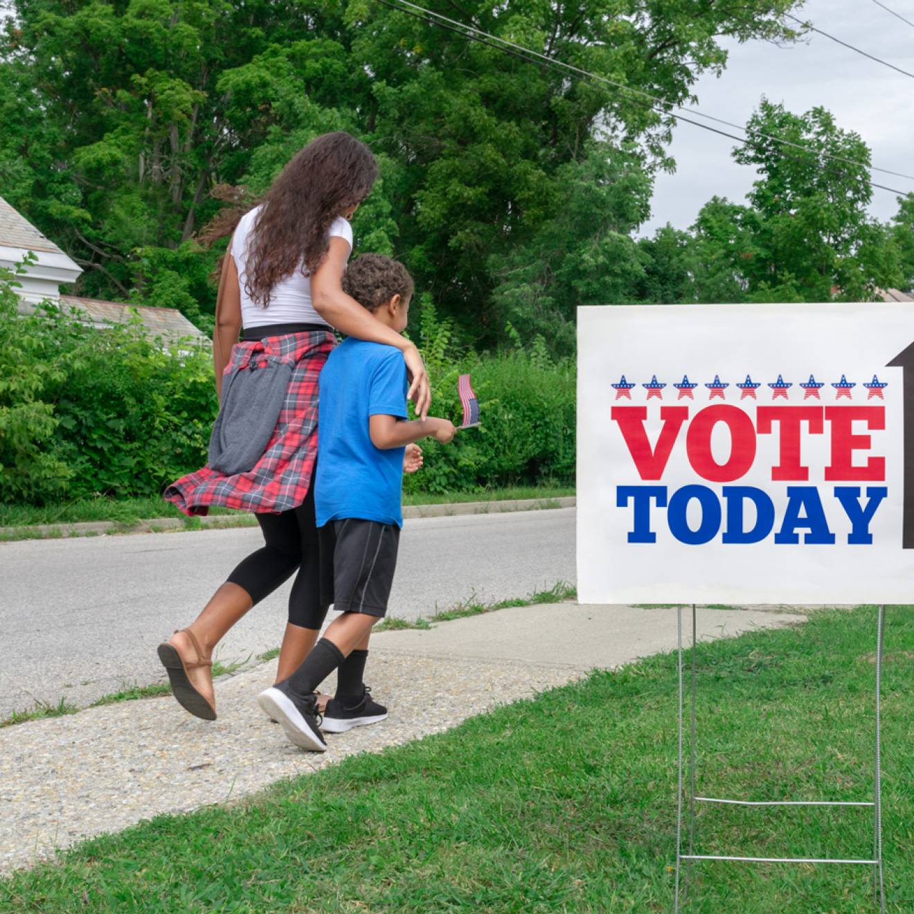 A Black woman and her son walk past a Vote Today sign to the polls