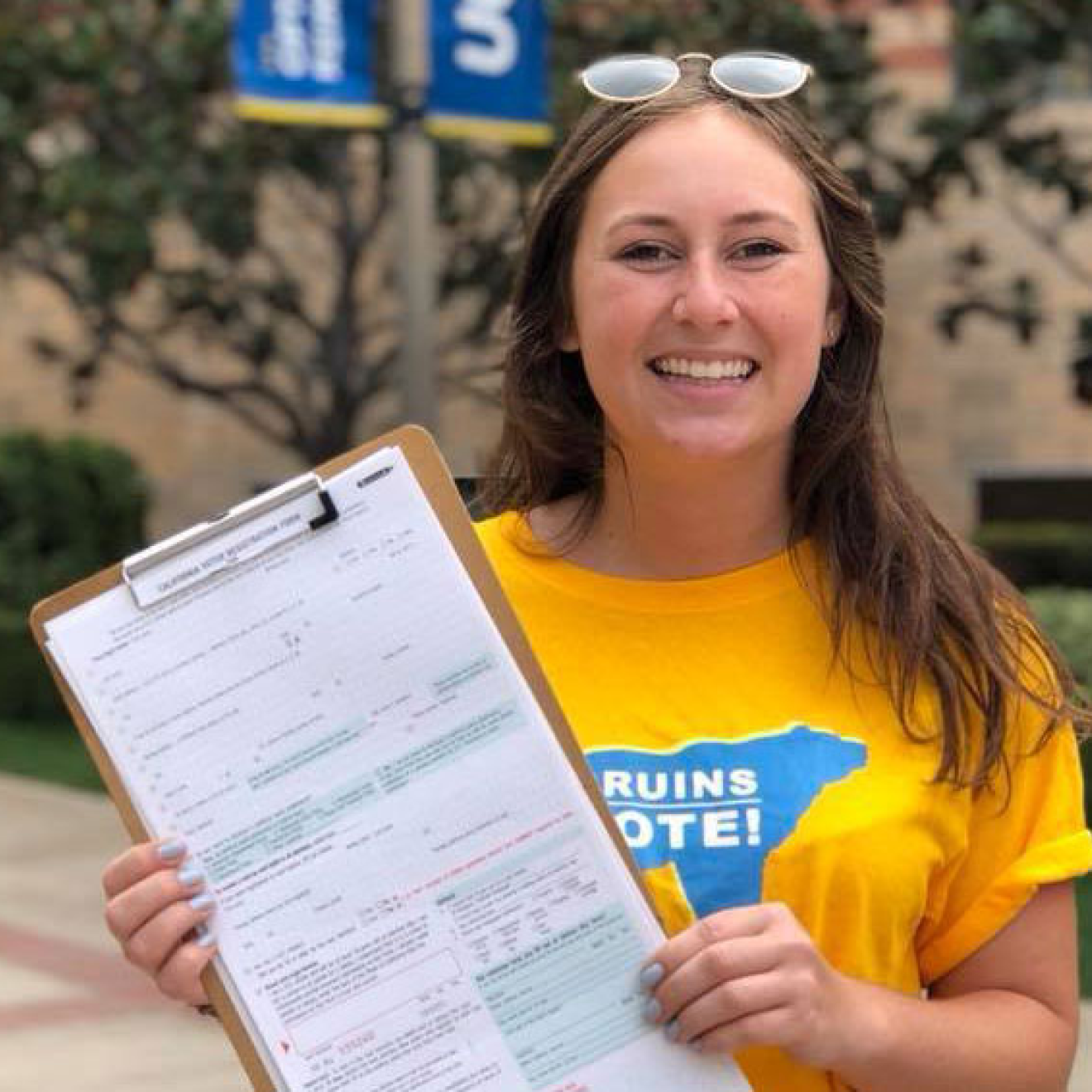 Young woman with Bruins Vote T-shirt holds up voter registration form