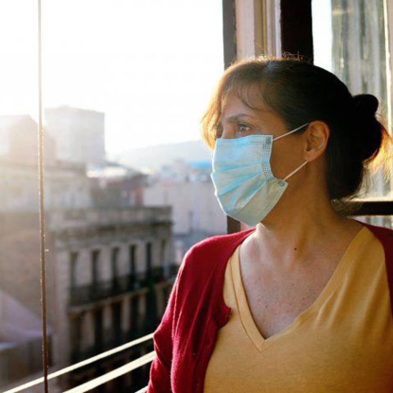 Woman in mask looks out the window