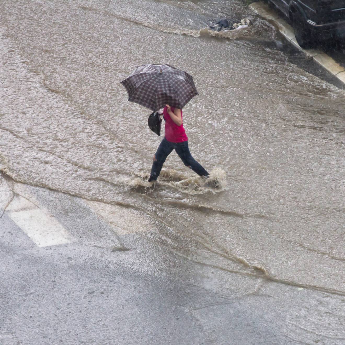 Woman walking through a flooded road with an umbrella