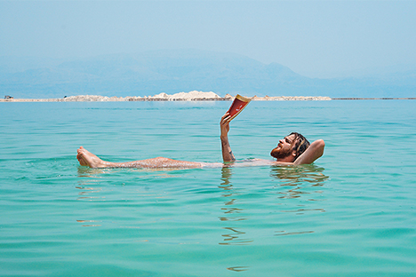 man reads while soaking in a lake