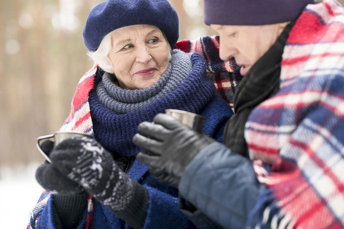 An older couple drinks tea in the snow