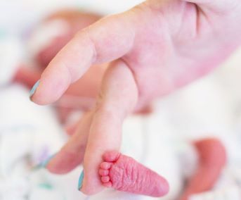 newborn baby foot with adult hand