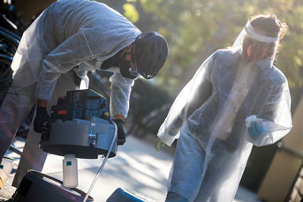 Two people in PPE collect wastewater samples