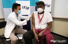 Image of a UCSF medical professional giving a COVID-19 vaccine dose to William Wyatt who was the first frontline health care hero at UCSF to receive a COVID-19 vaccine.